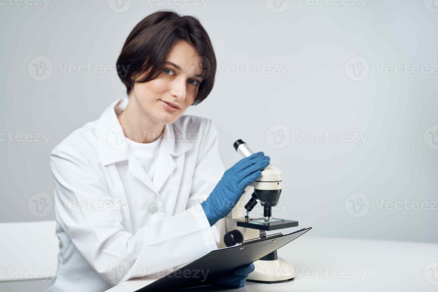 fêmea laboratório assistente olhando através uma microscópio diagnóstico pesquisa Ciência foto