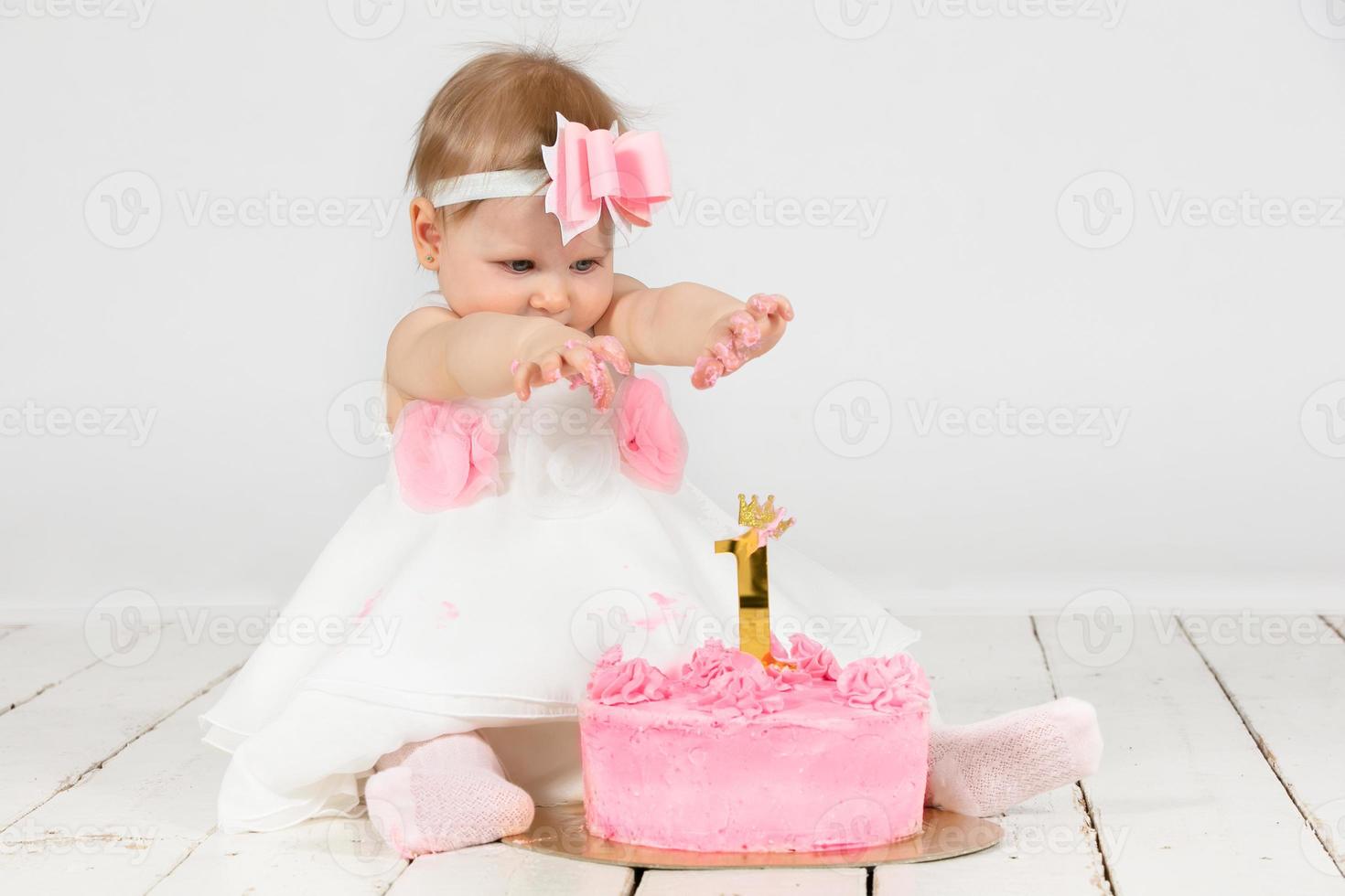 alegre criança com uma festivo bolo. engraçado menina dentro dela primeiro ano do aniversário. bebê 1 ano. foto