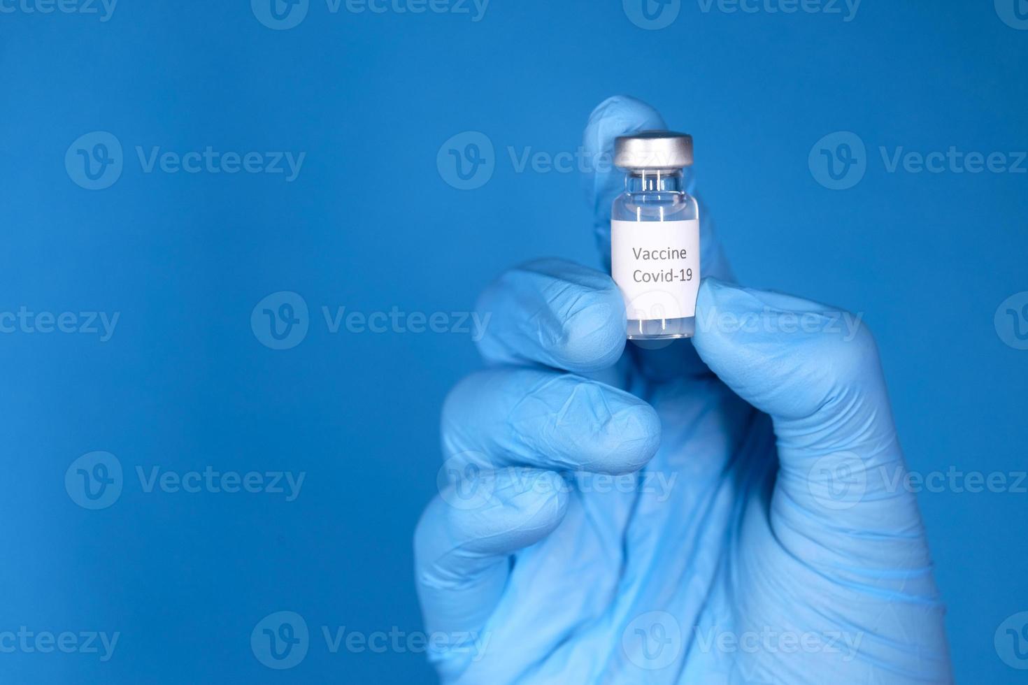vacina em uma pequena garrafa sobre fundo azul foto