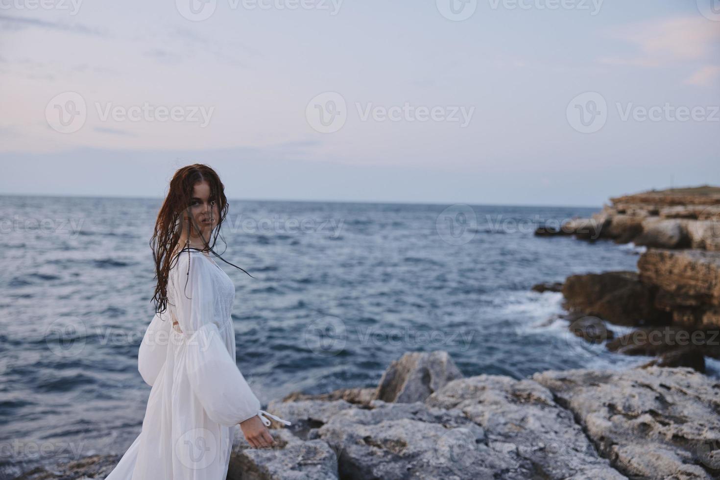 mulher com molhado cabelo dentro branco vestir posando de a oceano inalterado foto