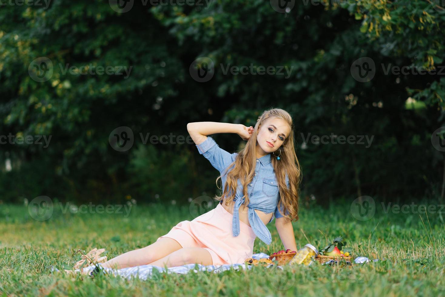 atraente alegre menina sentado em uma cobertor e gastos a final de semana relaxante dentro a parque ao ar livre foto