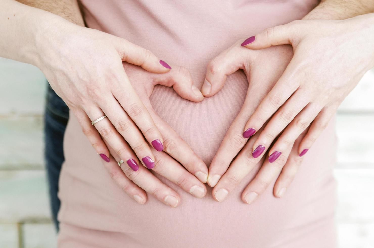 casal grávida com as mãos em forma de coração foto