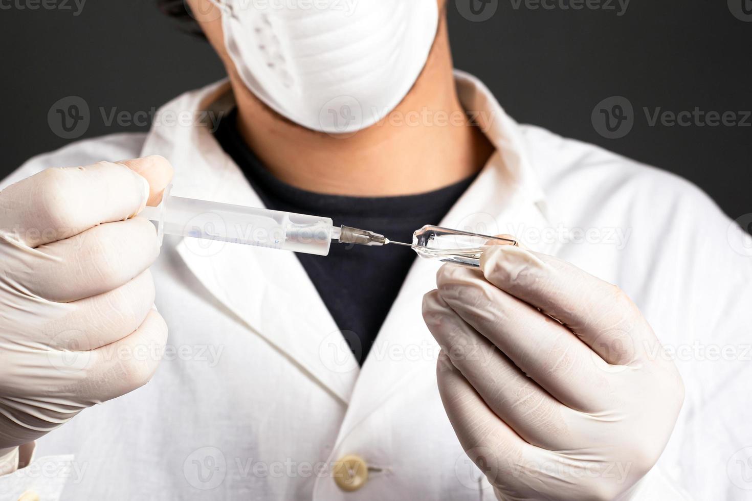 médico tira remédio de uma ampola para uma seringa foto