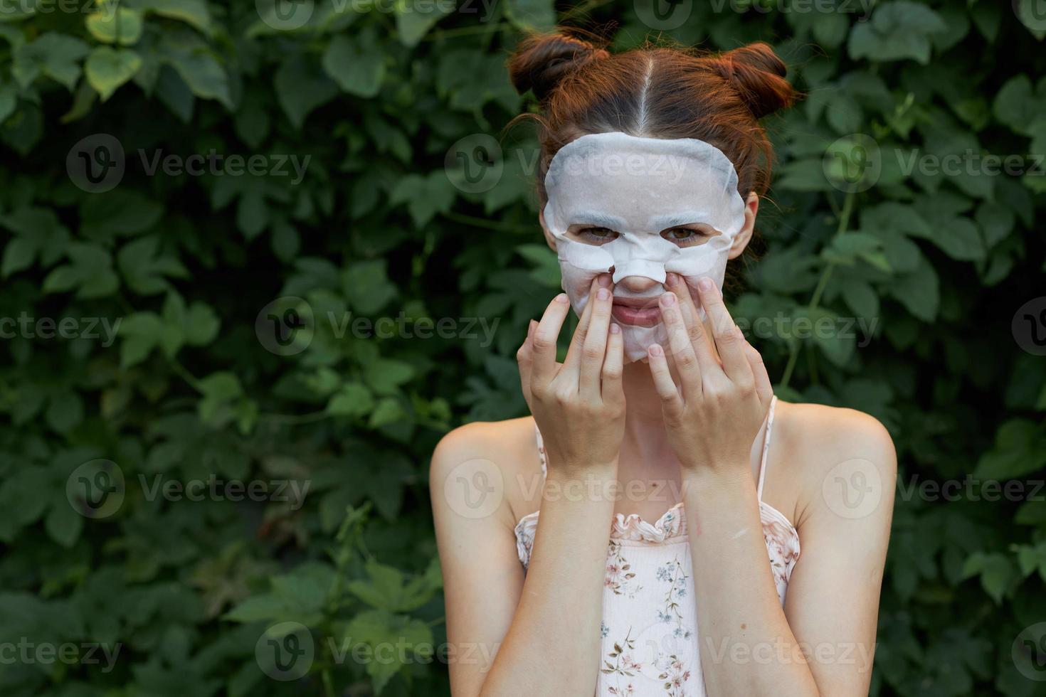 agradável menina anti-rugas mascarar pressione seu dedos em seu bochechas rejuvenescimento folhas dentro a fundo foto