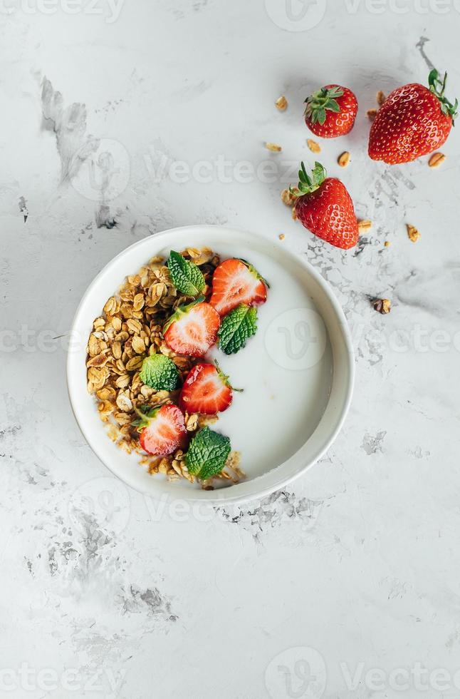saudável café da manhã conceito. tigela com granola, iogurte e bagas em branco mármore fundo foto