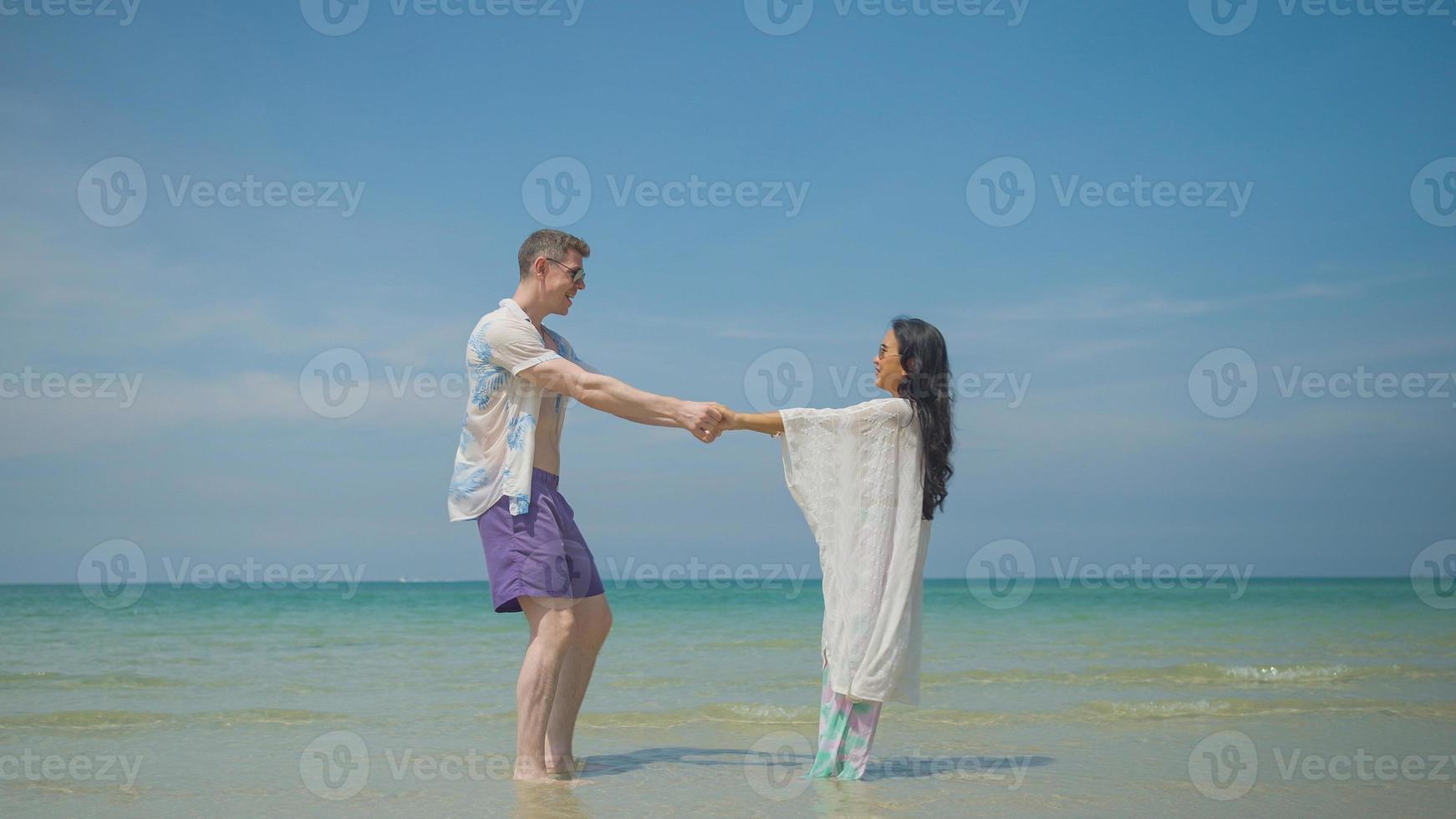 casais aguarde mãos e andar ao longo a de praia em seus verão período de férias e elas sorrir e ter Diversão em período de férias. foto