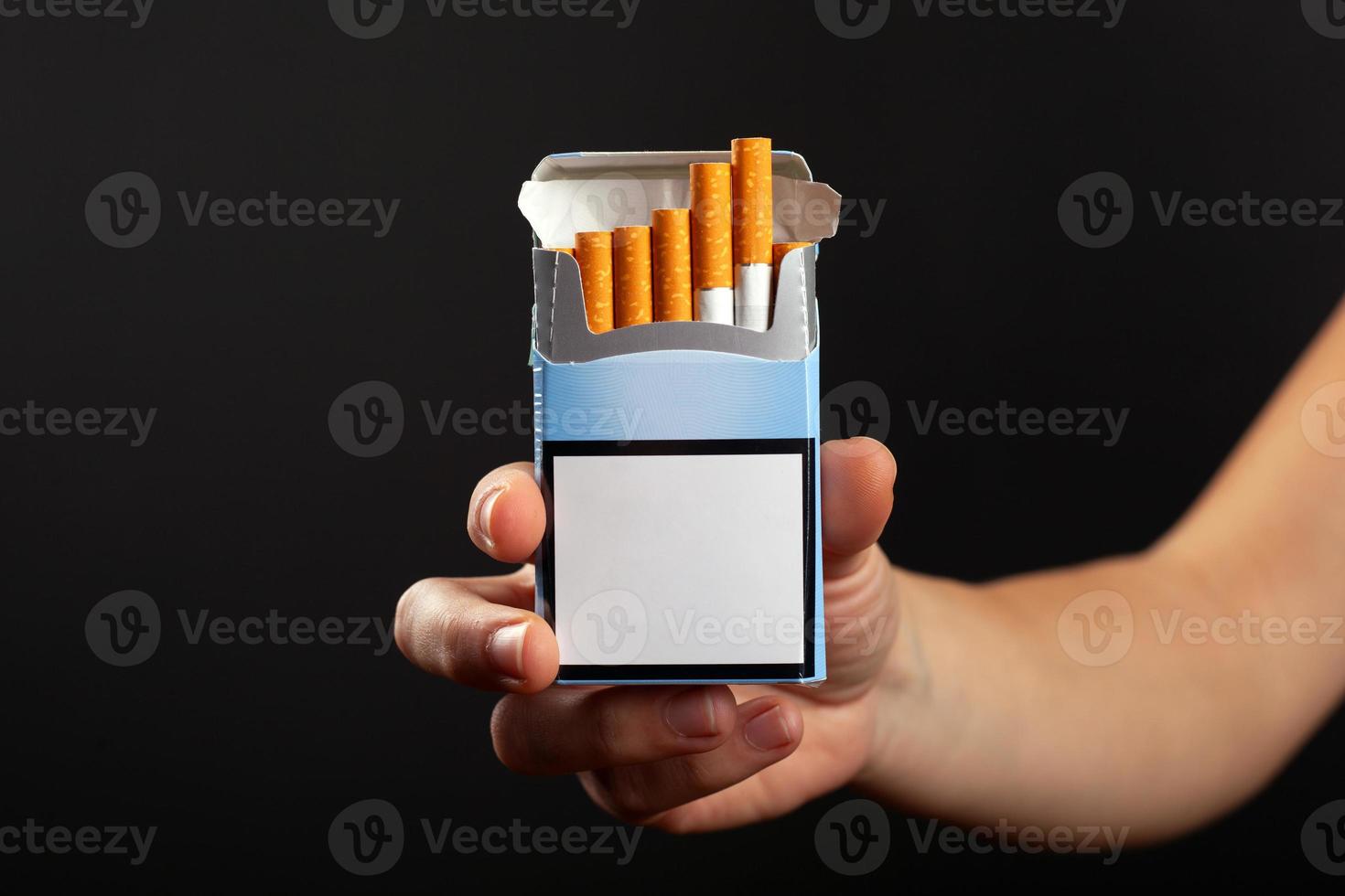 maço de cigarros azul na mão em um fundo escuro, maquete foto