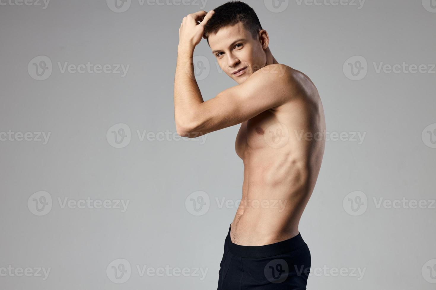 atleta com nu tronco mostrando braço músculos em cinzento fundo cortada Visão do fisiculturista ginástica foto