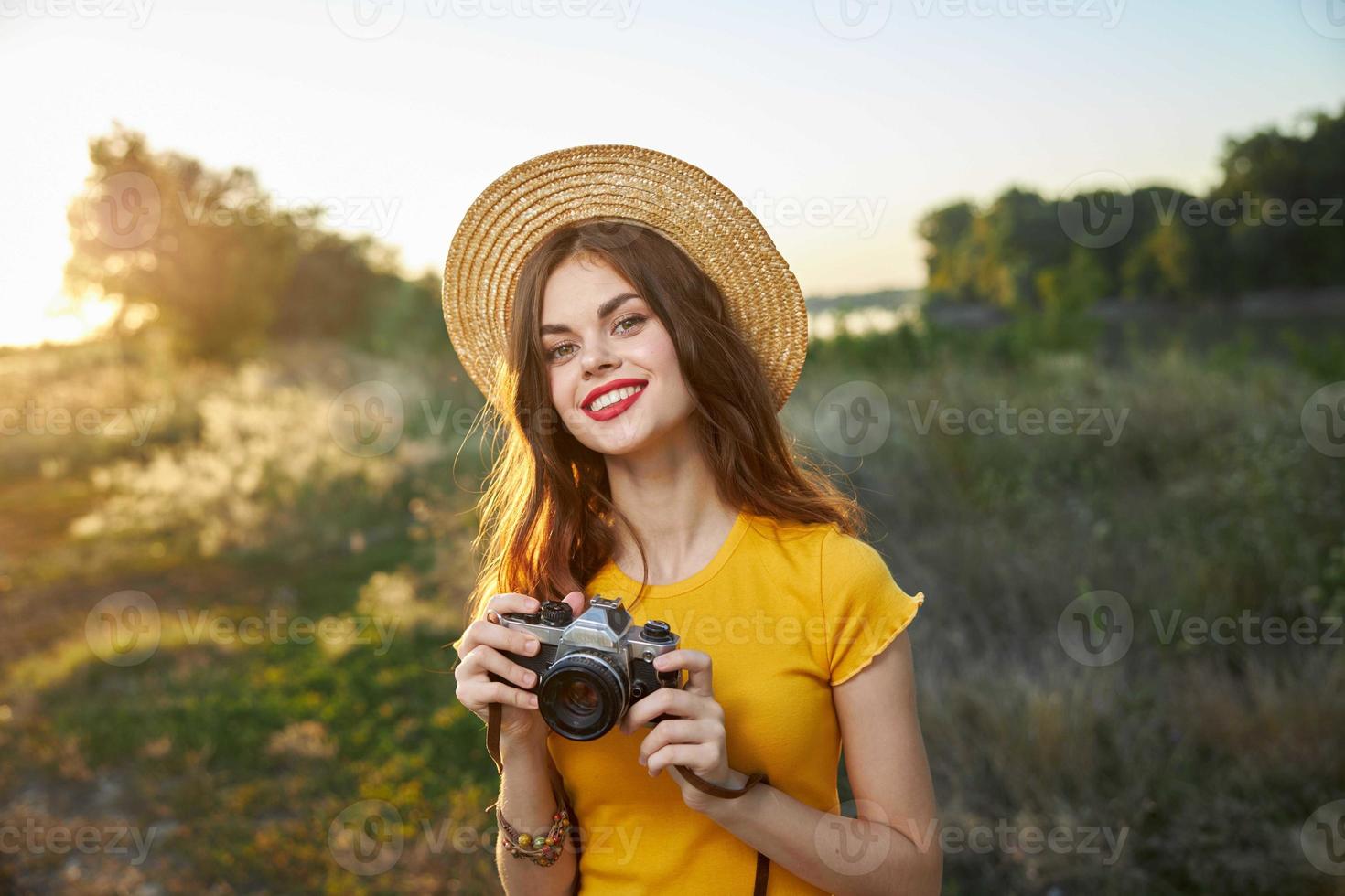 mulher dentro uma chapéu com uma Câmera dentro dela mãos vermelho lábios atraente Veja natureza foto