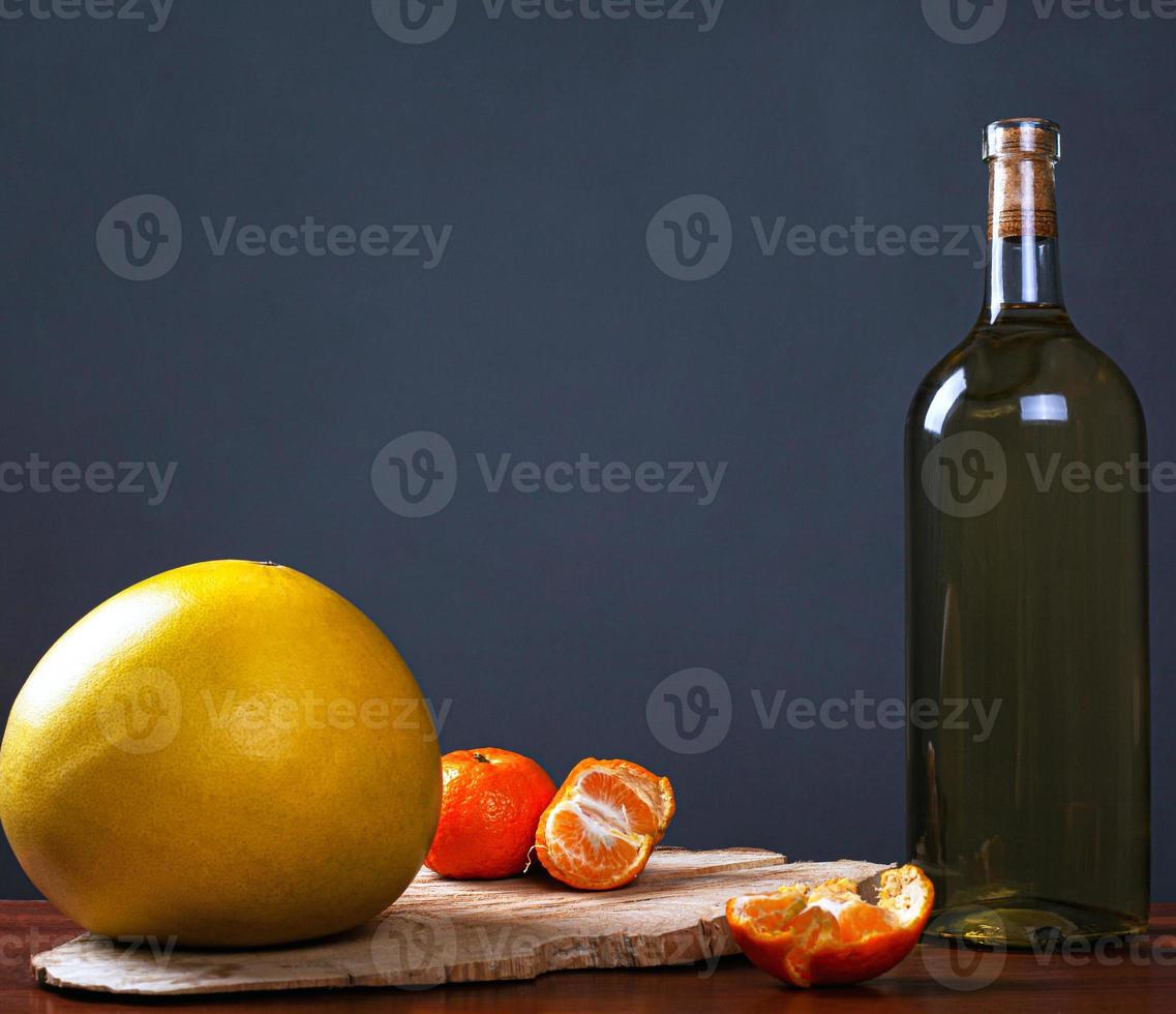 garrafa de vinho branco com frutas tropicais em uma floresta rústica fica em um fundo escuro foto