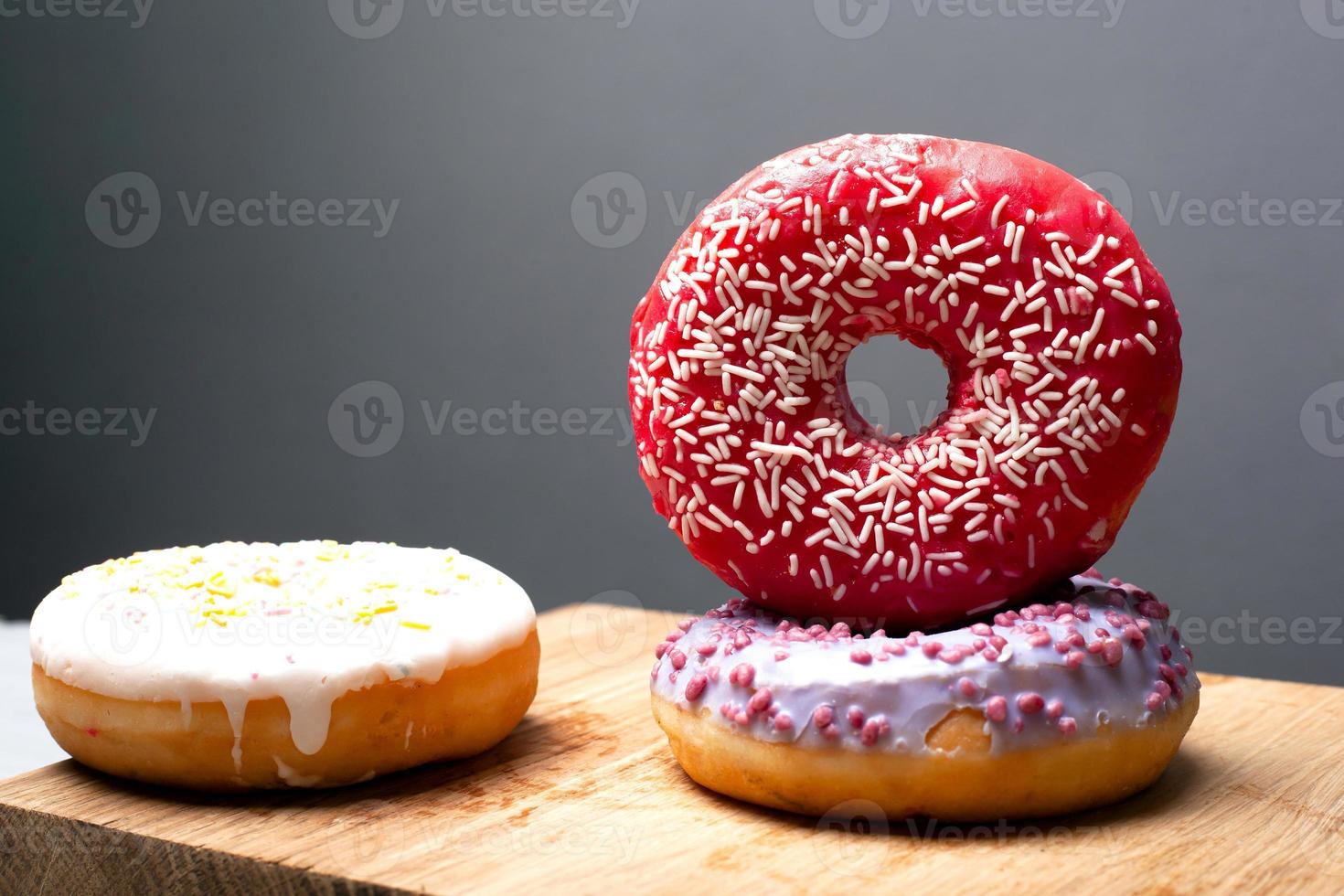 donuts multicoloridos de férias em pó em um suporte de madeira sobre um fundo cinza foto