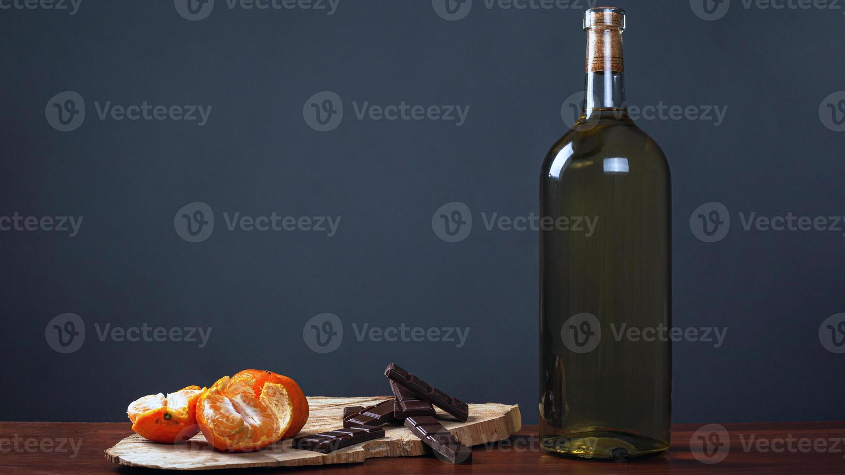 jantar romântico com uma garrafa de vinho com chocolates doces e tangerinas foto