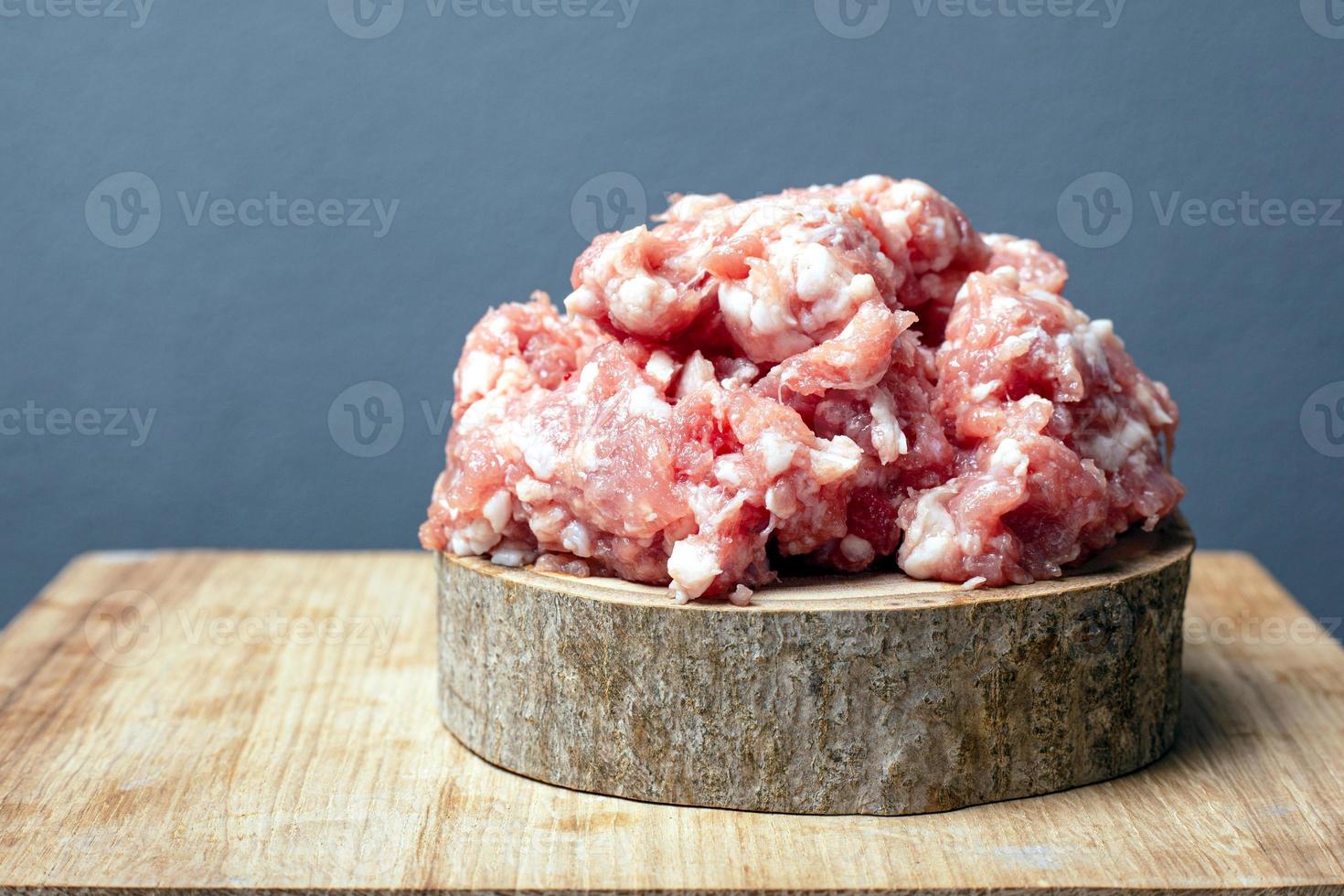 Carne de porco crua fresca picada em uma placa de madeira em um fundo cinza foto