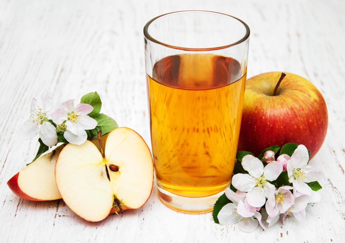 copo de suco de maçã com maçãs e flores em um fundo de madeira foto