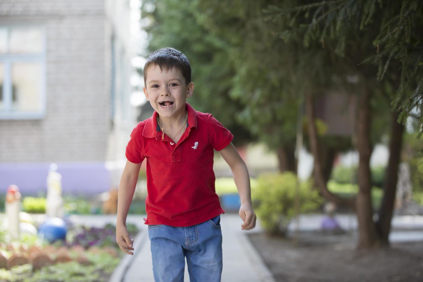 engraçado pré-escolar criança é caminhando baixa a rua. seis ano velho alegre Garoto em uma verão dia. foto