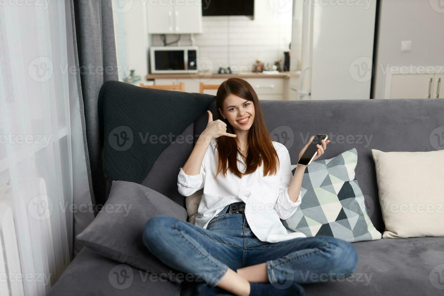 alegre mulher falando em a telefone sentado em a sofá em repouso dentro a apartamento foto