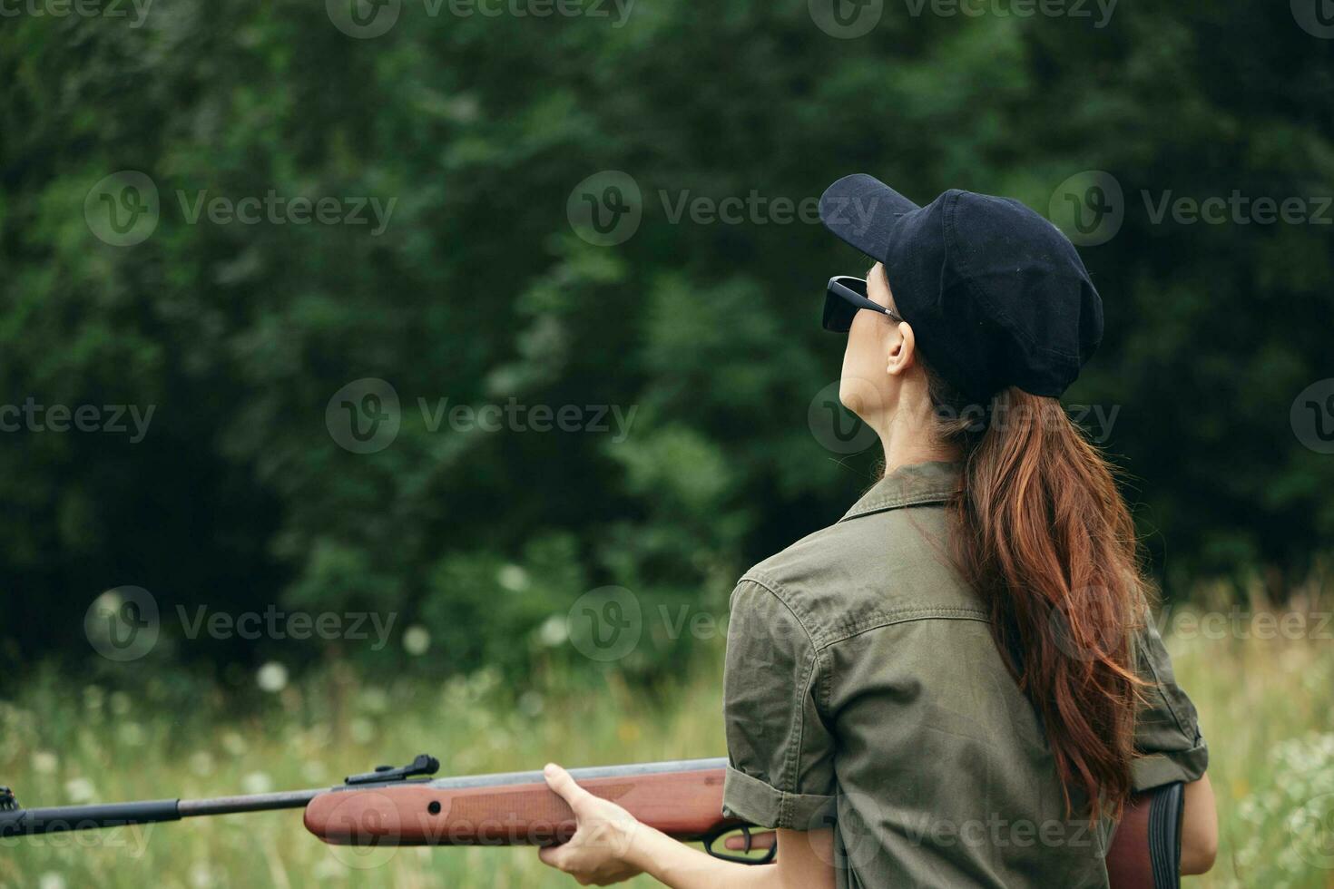 mulher soldado com uma arma de fogo dentro dele mãos Sombrio óculos costas Visão fresco ar foto