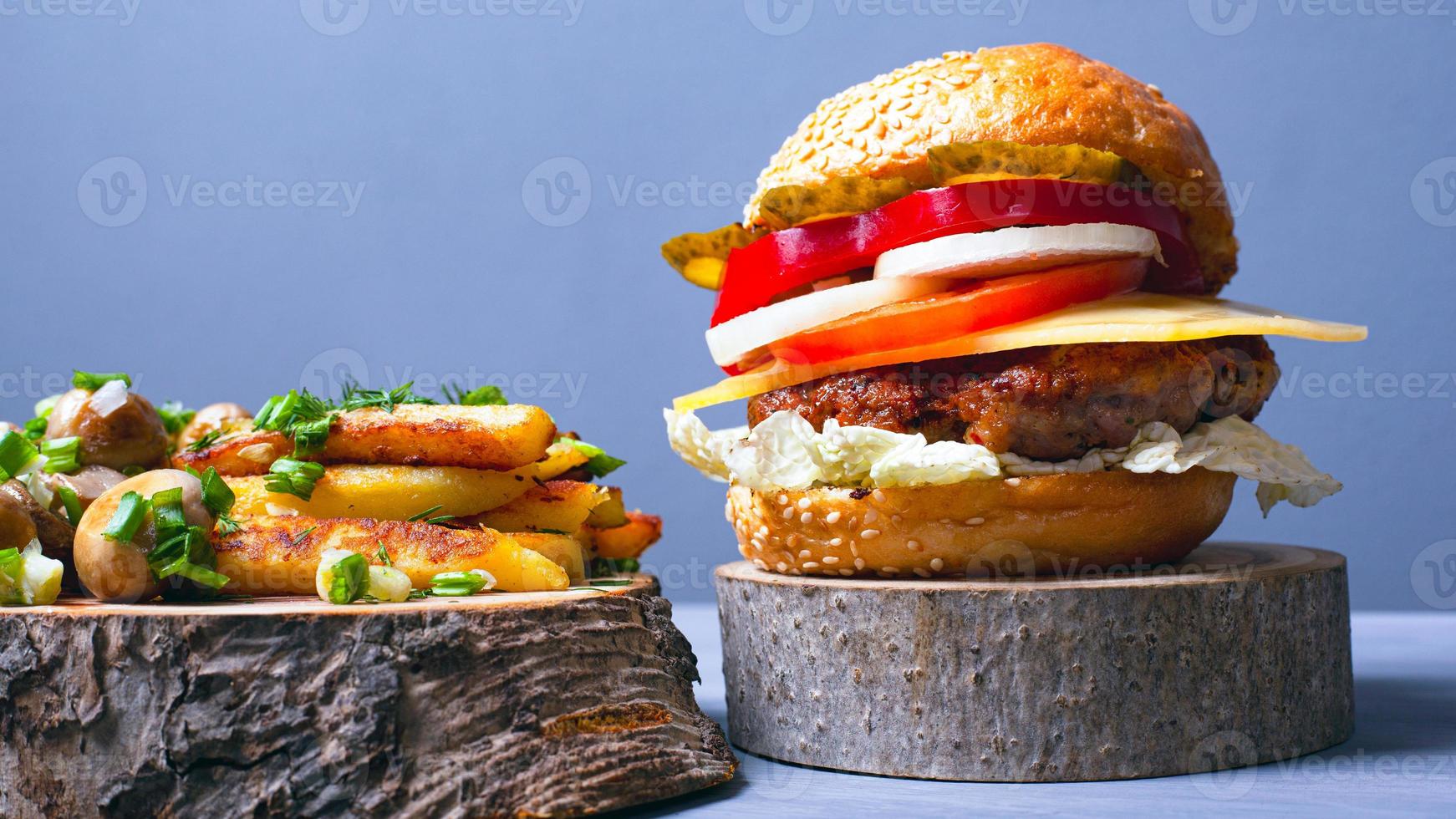 hambúrguer saboroso com costeleta de carne, legumes e queijo com pão macio, batatas fritas e cogumelos champignon foto