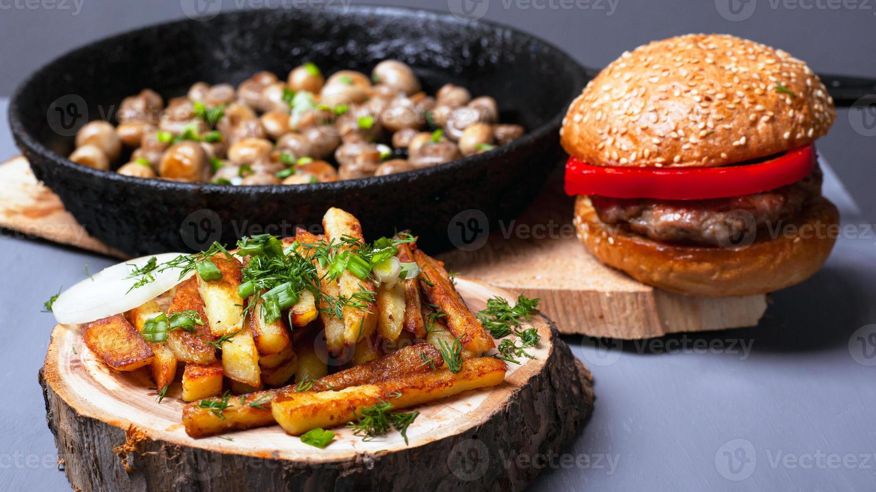 batatas fritas, hambúrguer e cogumelos fritos em um fundo cinza, close-up foto