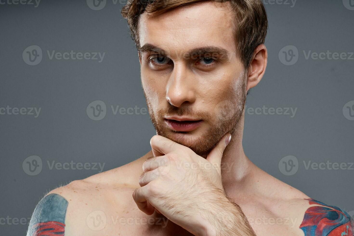 retrato do jovem homem com tatuagens em cinzento fundo e lindo face modelo cortada Visão foto