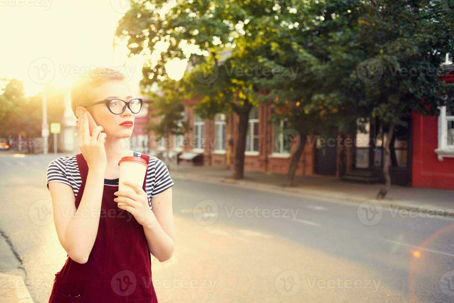 bonita mulher com óculos em a rua falando em a telefone dentro verão foto