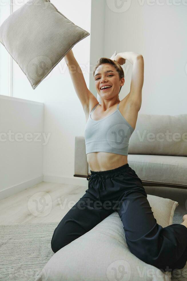 Adolescência menina sorrir todos senta às casa perto a sofá e lança acima travesseiros, Diversão jogos e felicidade sem filtros, cópia de Lugar, colocar foto