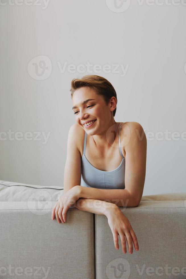 feliz mulher sorrir deitado às casa em a sofá relaxante em uma final de semana às casa com uma curto corte de cabelo cabelo sem filtros em uma branco fundo, livre cópia de espaço foto