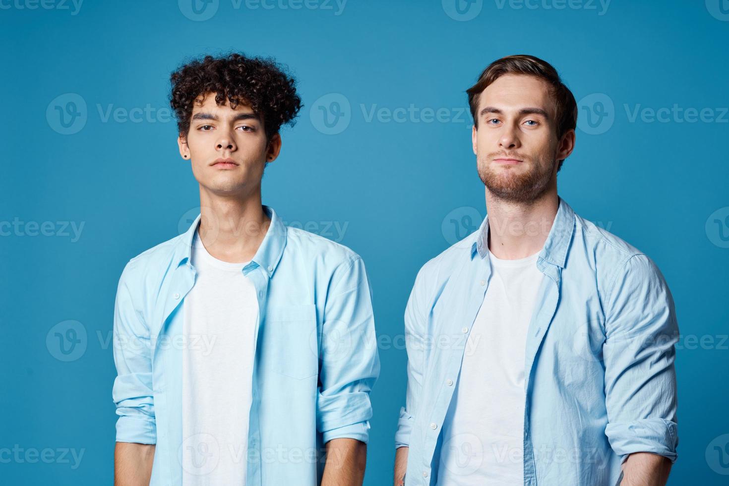 dois amigos dentro idêntico camisas e uma camiseta gesticulando com seus mãos em uma azul fundo foto