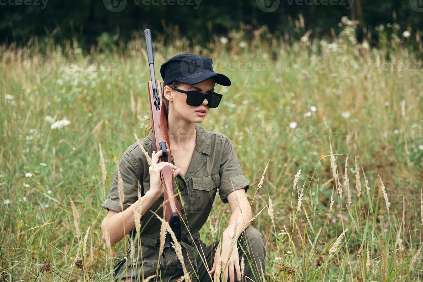 mulher com uma arma em dele ombro vestindo Sombrio óculos para cobrir fresco ar verde foto