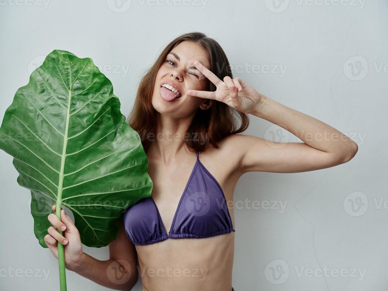 alegre mulher mostrando língua dentro roupa de banho verde folha trópicos isolado fundo foto