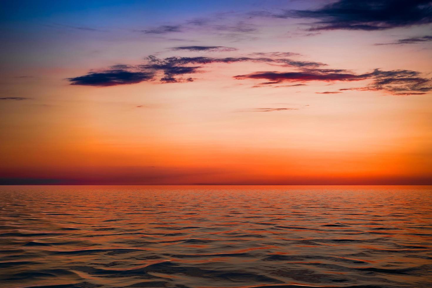 pôr do sol nublado colorido sobre um corpo de água foto
