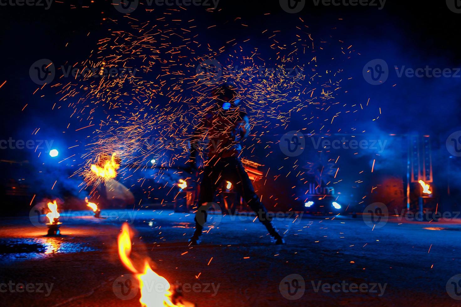 show de fogo, dançando com chamas, mestre masculino fazendo malabarismo com fogos de artifício, performance ao ar livre, desenha uma figura de fogo no escuro, faíscas brilhantes à noite. um homem de terno conduzia danças com fogo foto