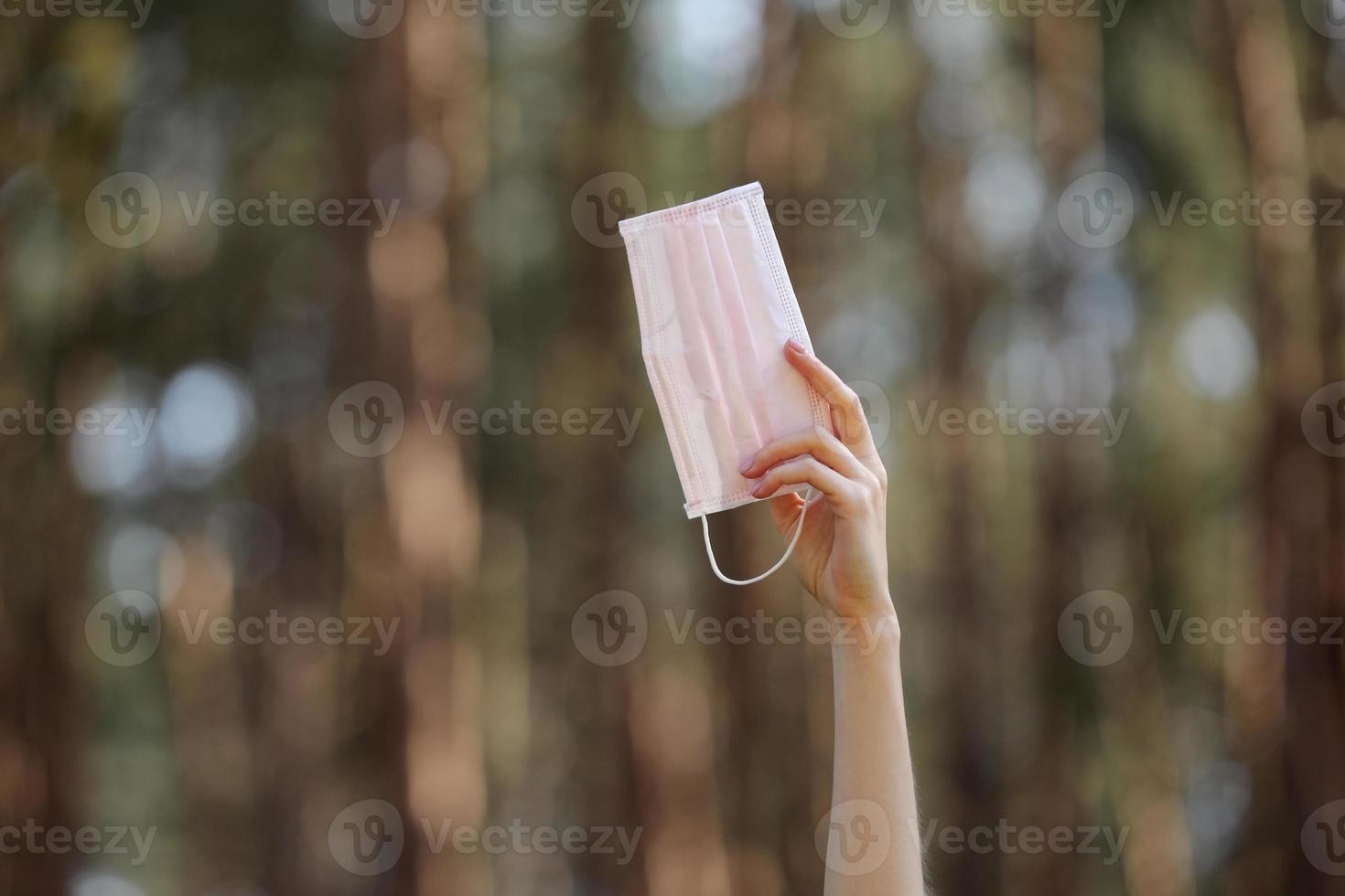 máscara protetora médica na mão da menina isolada no fundo da natureza. proteção de máscara facial contra infecção de vírus. coronavírus - 2019. conceito de cuidados de saúde. foco seletivo. foto