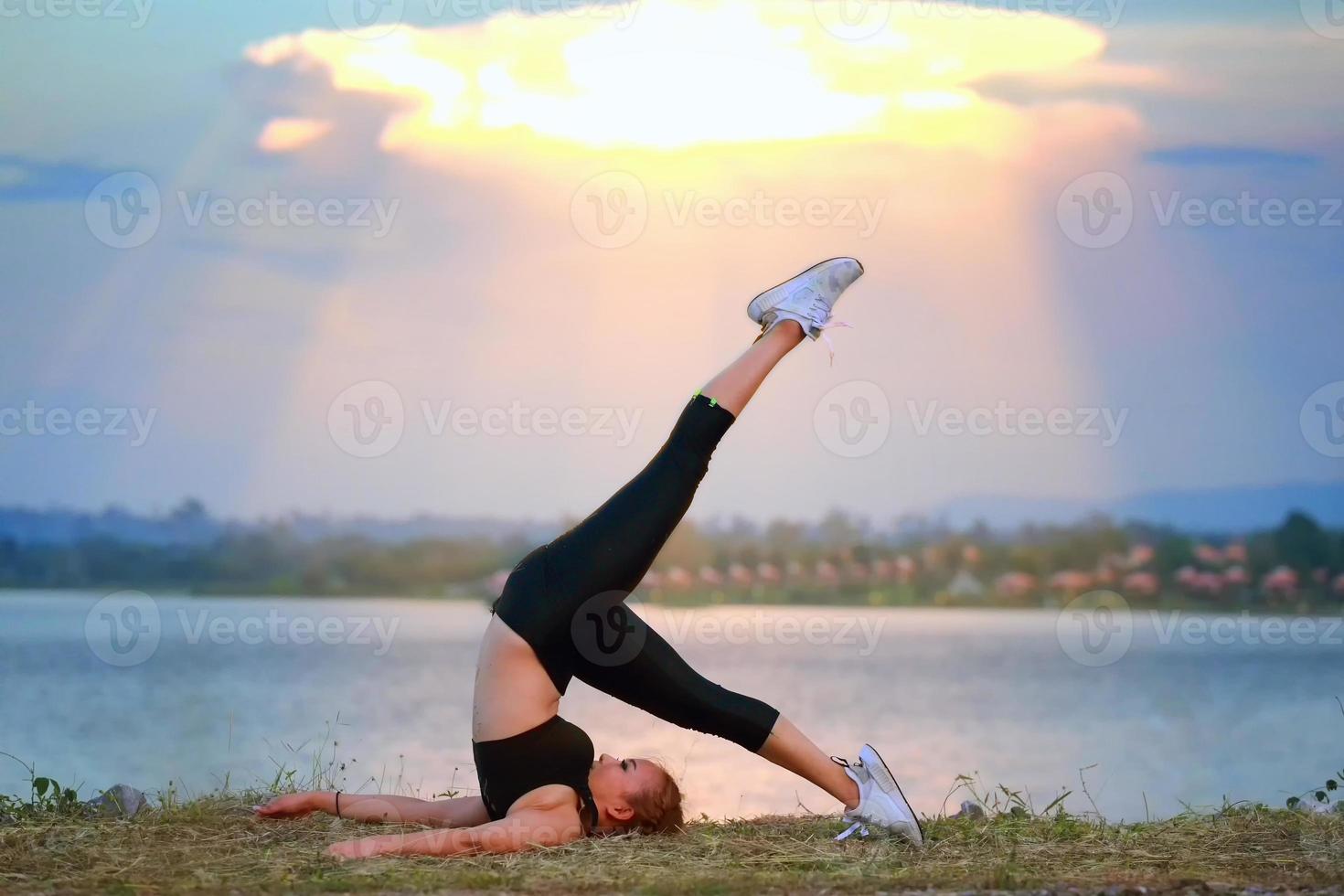 jovem menina fazendo ioga ginástica exercício manhã nascer do sol ao ar livre dentro a Prado lindo montanhas panorama. meditação e relaxar. foto