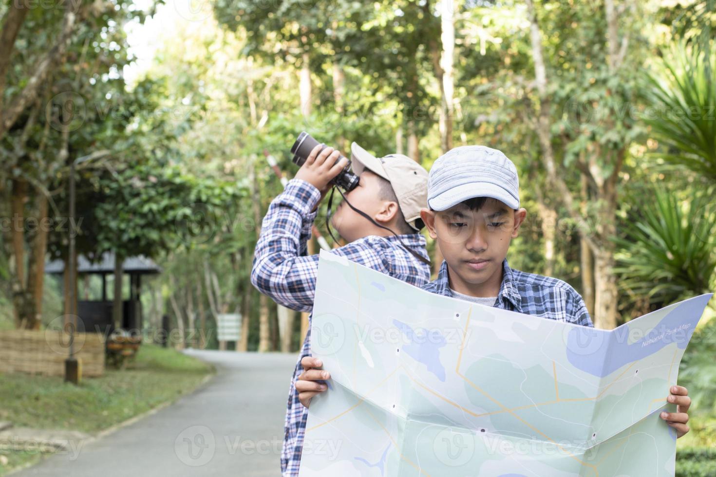 ásia Rapazes usando binóculos para Faz a observação de pássaros dentro tropical floresta durante verão acampamento, idéia para Aprendendo criaturas, animais selvagens animais e insetos lado de fora a sala de aula. foto