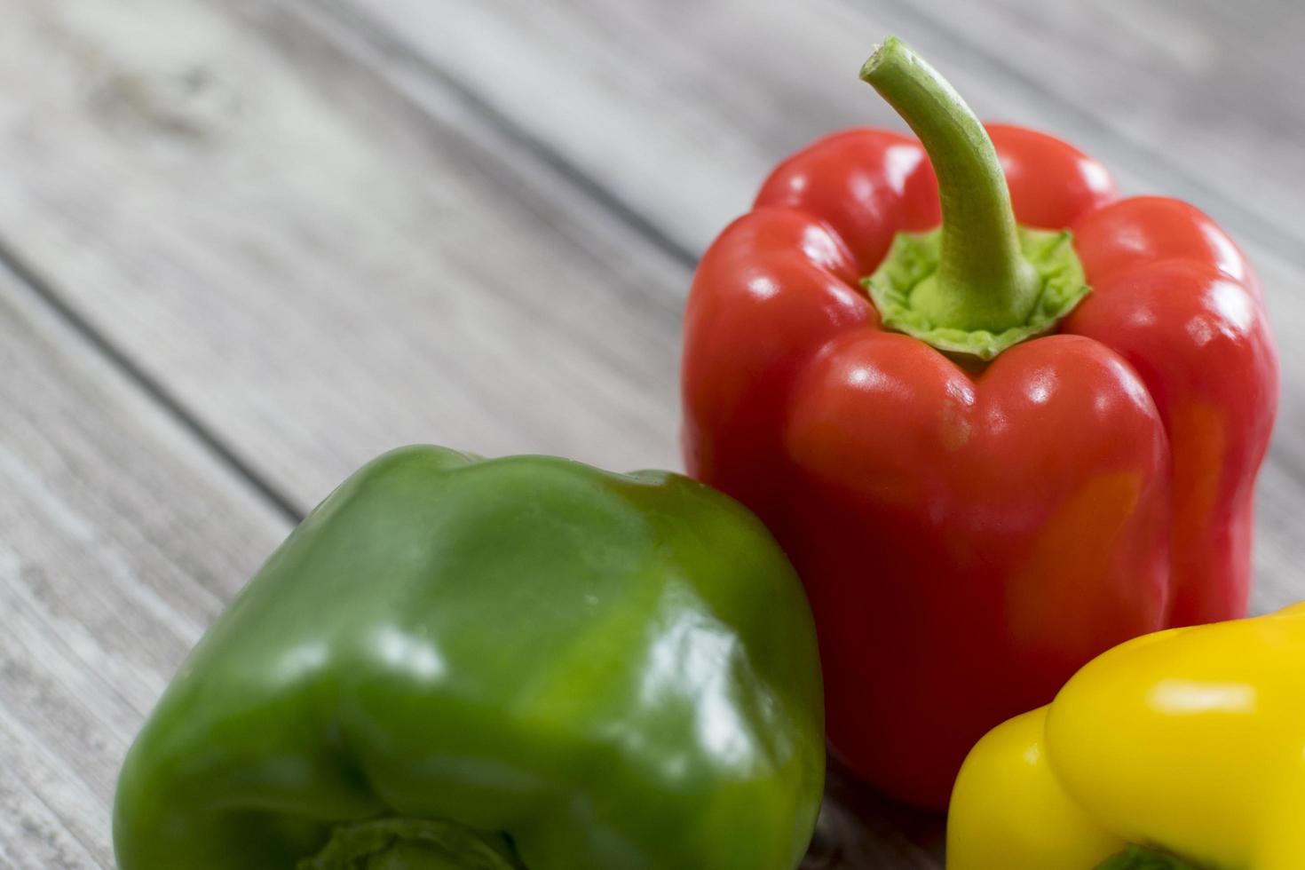 pimenta vermelha, verde e amarela, em uma mesa de madeira. foto