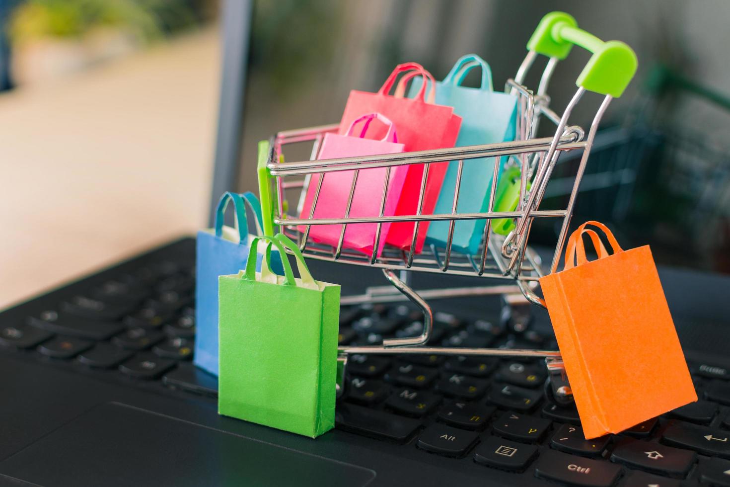 sacolas de papel coloridas no carrinho de compras em um teclado de computador portátil. compras online de sites através do conceito de internet. foto