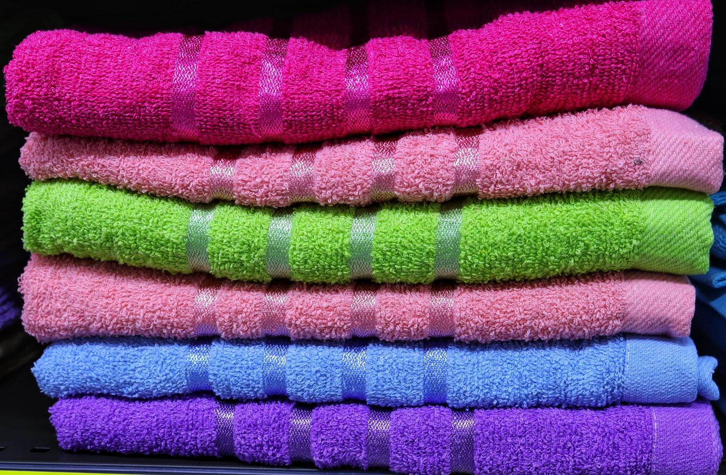 cuidadosamente arranjado Grosso algodão brilhante cor toalhas dentro prateleiras foto