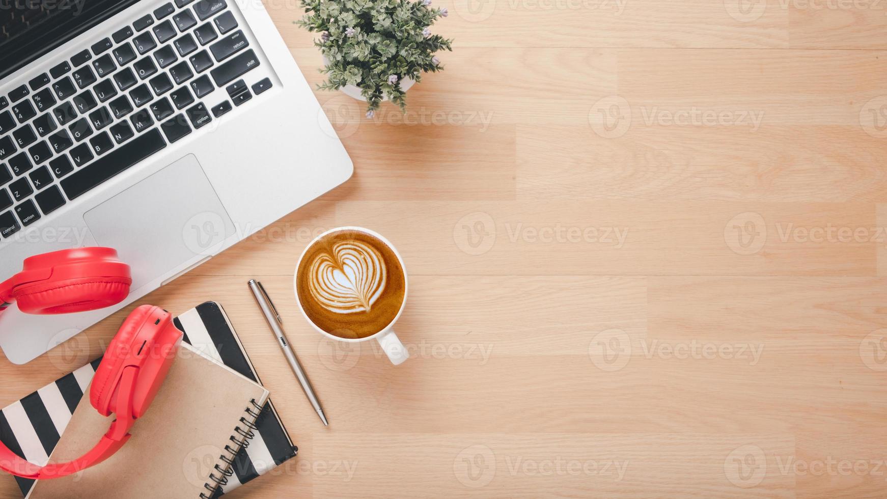 escritório escrivaninha local de trabalho com computador portátil computador, fone de ouvido, caderno, caneta e copo do café, topo Visão plano deitar com cópia de espaço. foto