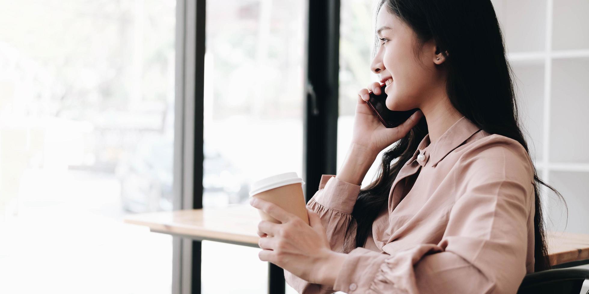 mulher falando ao telefone e segurando um café foto