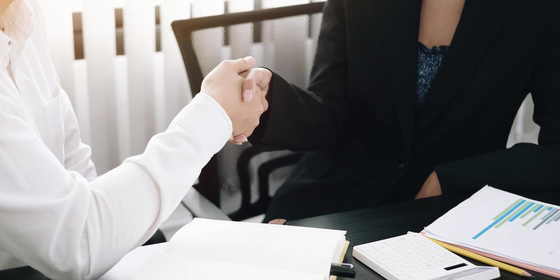 dois profissionais apertando as mãos em uma mesa foto