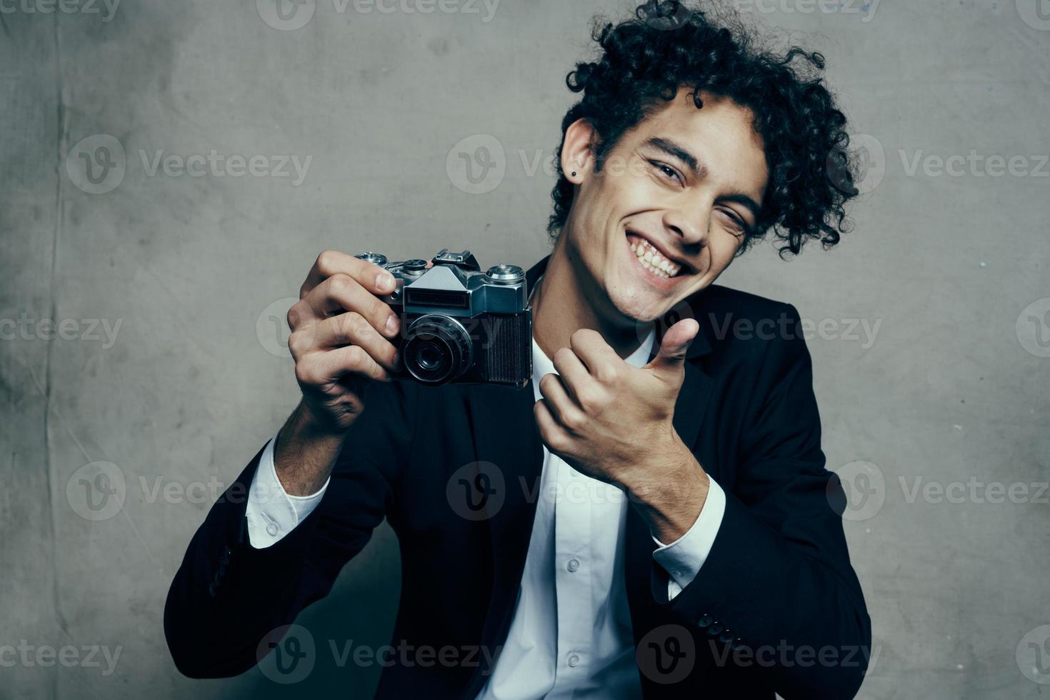 fofa cara segurando Câmera clássico terno gesticulando com mãos sorrir alegria modelo foto