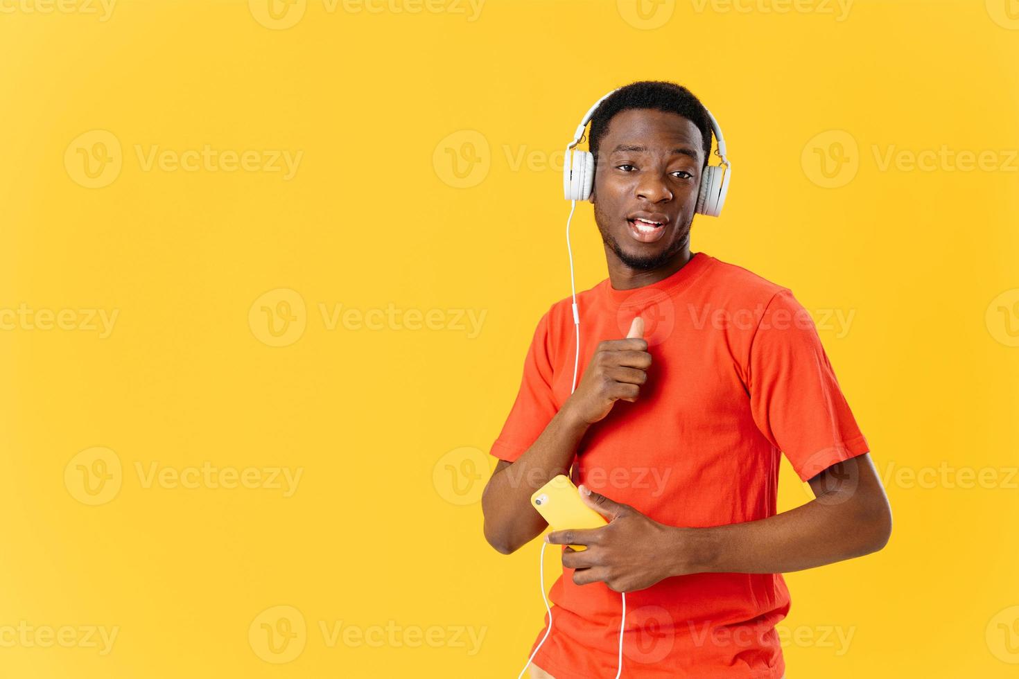 homem fone de ouvido telefone dentro mãos tecnologia música amarelo fundo foto