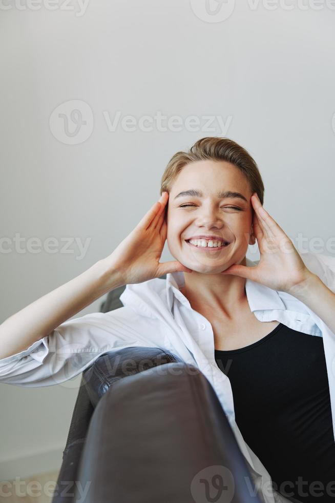 mulheres deitado às casa em a sofá retrato com uma curto corte de cabelo dentro uma branco camisa, sorriso, depressão dentro adolescentes, casa feriado foto