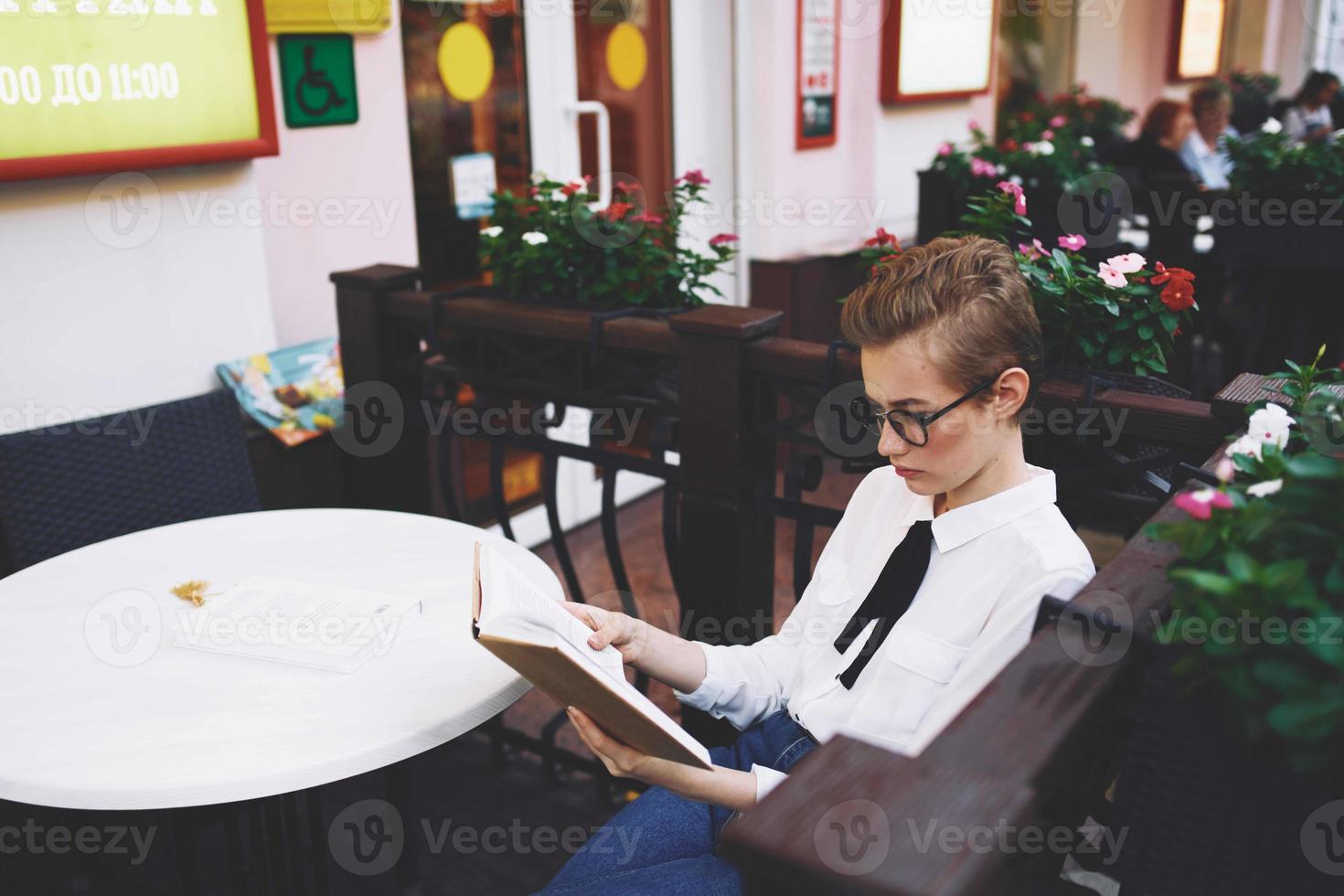 aluna com uma livro dentro dele mãos ao ar livre dentro uma verão cafeteria descansar comunicação foto