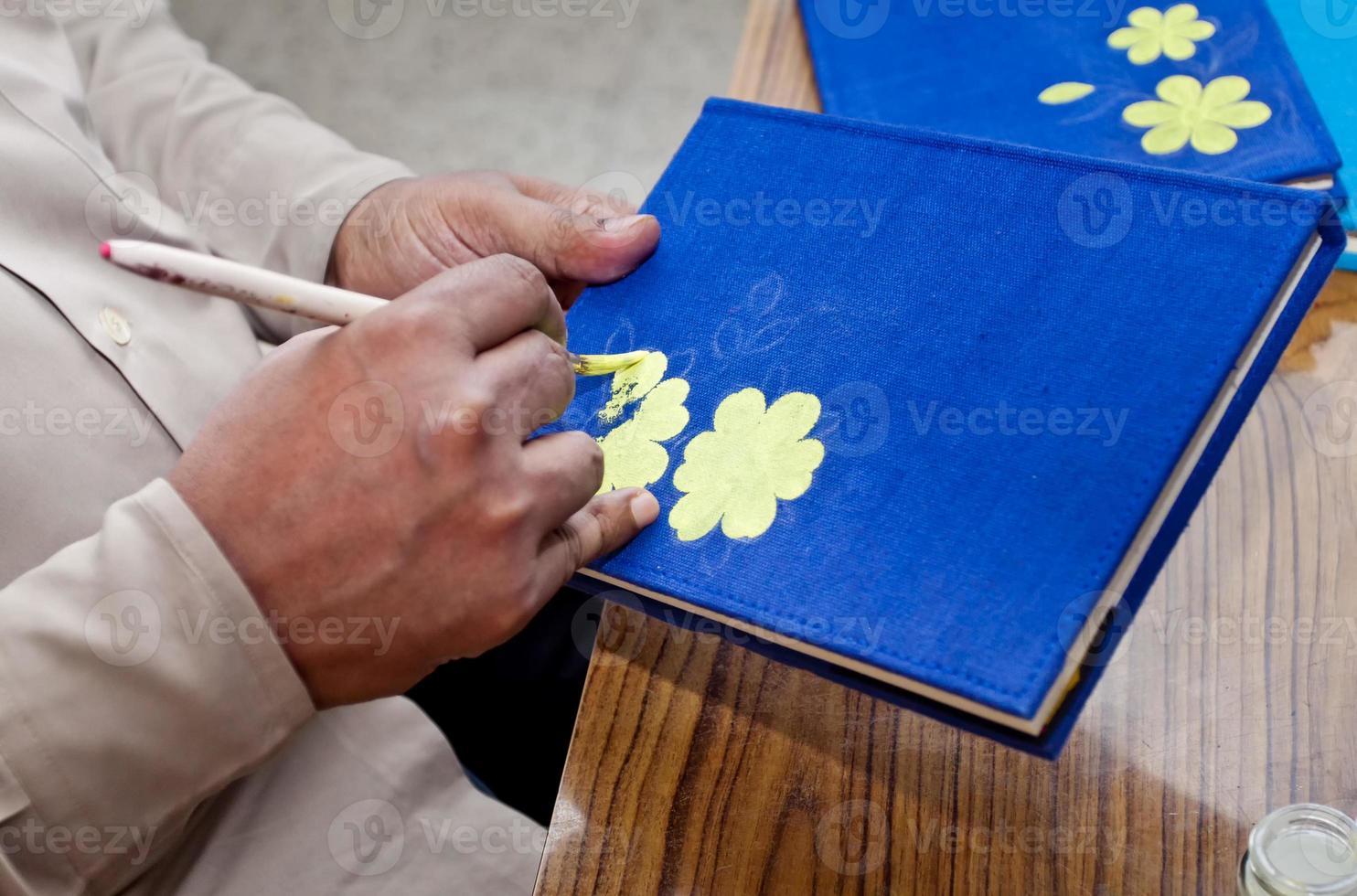 uma artesanato artista é pintura em uma feito à mão livro cobrir em casa estúdio área de trabalho. foto