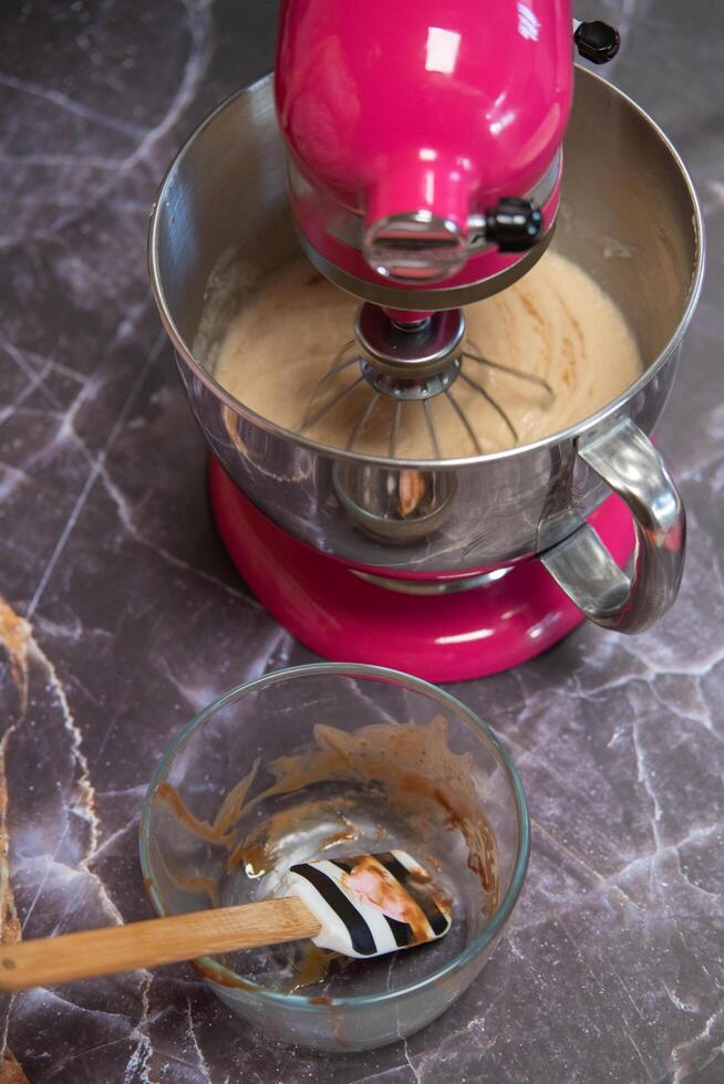 tigela com chocolate ao lado de uma batedeira em um fundo de mármore escuro foto