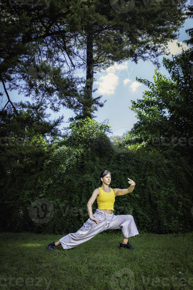 mulher praticando tai chi quan dentro a parque. tai chi é uma fisica e mental prática originário dentro China este combina suave, fluindo movimentos com respiração e meditação técnicas. foto