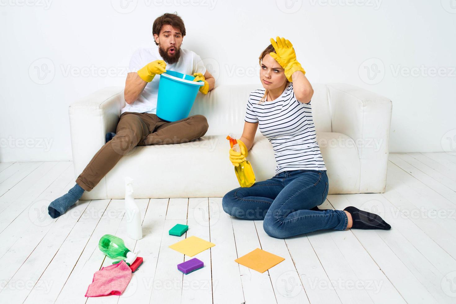 mulher lavagens a pavimentos uma homem senta em a sofá às casa interior limpeza foto