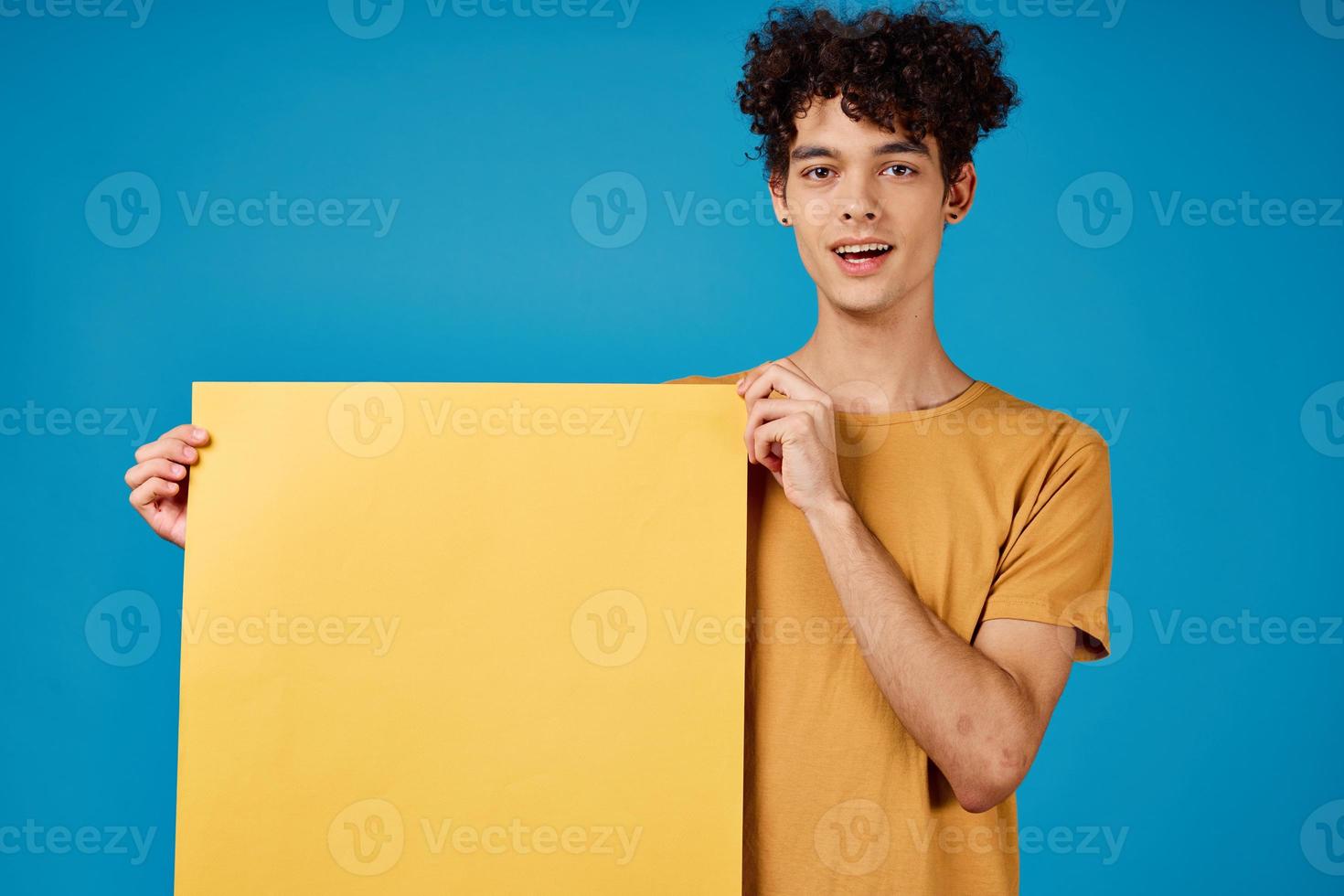 alegre homem com encaracolado cabelo amarelo poster publicidade azul fundo foto